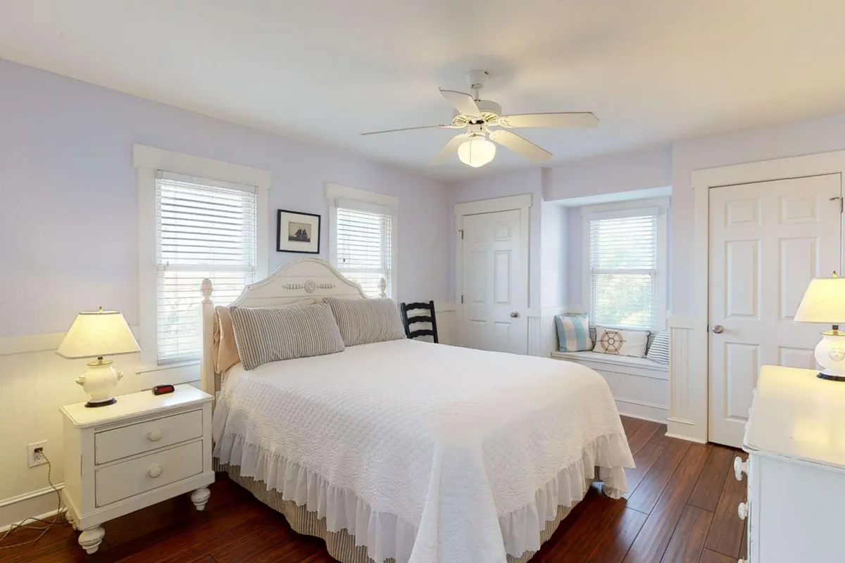 A serene bedroom featuring a comfortable bed, nightstand, and a window seat that looks out onto peaceful views. The dresser and cozy decor invite relaxation, making it a perfect spot for both restful sleep and leisurely mornings.
