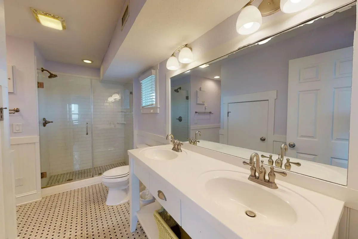 A spacious, modern bathroom with a double sink vanity, large mirror, and a walk-in shower. Clean lines and soothing colors create a refreshing, tranquil space ideal for self-care routines and relaxation after a long day.