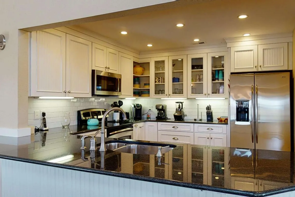 A bright, modern kitchen space featuring a sleek granite countertop, stainless steel appliances, and elegant glass-front cabinets. The setup feels perfect for both casual brunches and more formal gatherings, reflecting a well-equipped environment for culinary creativity.