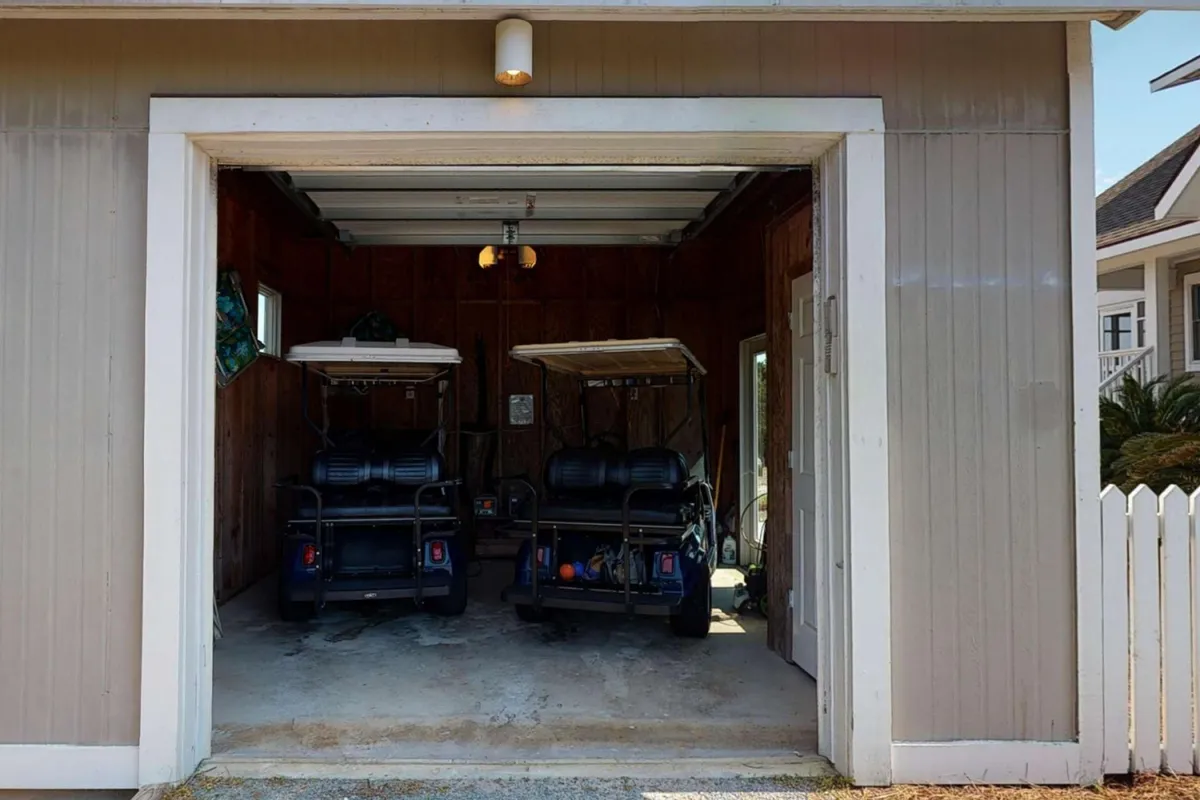 Two 4-seat golf carts are neatly parked inside a garage with wooden walls, emphasizing readiness for the next island adventure. The carts are the focal point, highlighting the ease with which guests can load up and set off to explore the beach, marina, or club amenities.