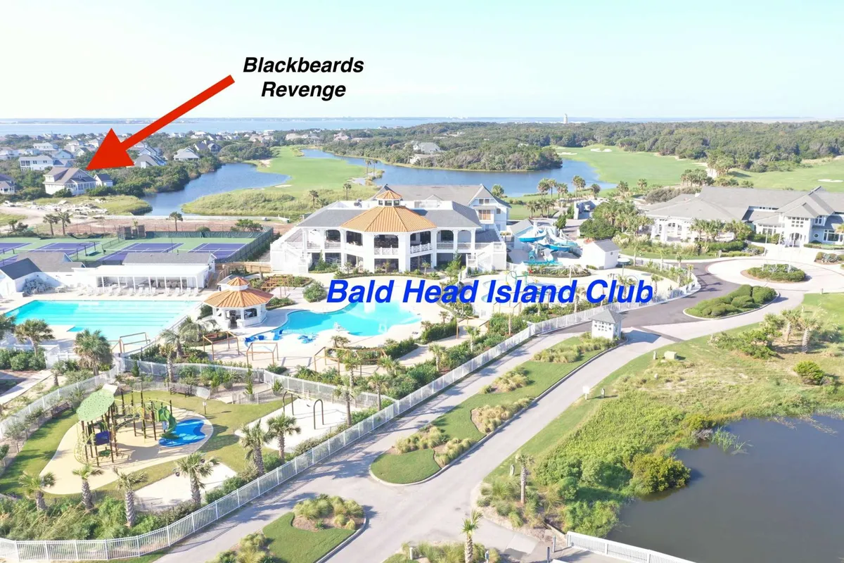 This image showcases the Bald Head Island Club, complete with its inviting swimming pools, manicured gardens, and nearby Blackbeard’s Revenge. The scene includes sunlit spaces for social gatherings and recreational activities such as swimming, golfing, and relaxing by the pool.
