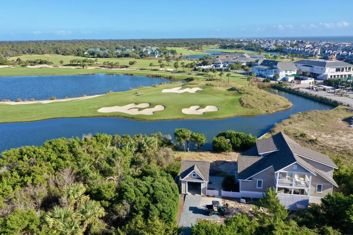The image showcases a beautifully maintained house overlooking a tranquil pond and lush golf course, with sweeping views of the surrounding landscape. The scene hints at outdoor activities like golfing and nature walks, as well as opportunities for relaxing on the porch while enjoying sunrise or wildlife.