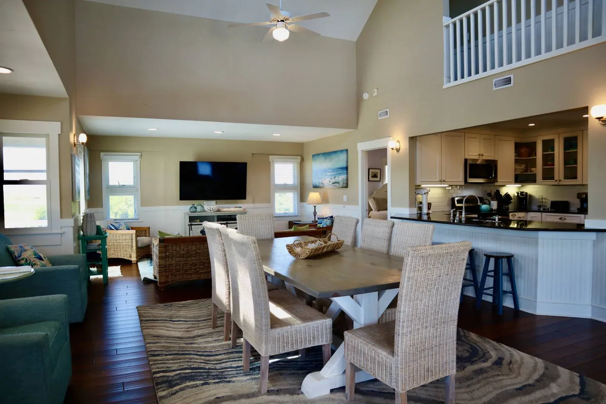 A spacious open-plan area that seamlessly integrates the dining table, kitchen, and a sofa seating area. The dining table is ideal for laughter-filled meals, while the connected living space and visible kitchen area reinforce the open design that keeps conversation flowing throughout the home.